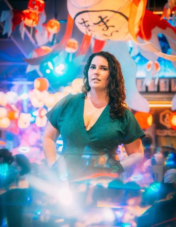 A woman in an emerald jumpsuit stands in a colorful area of the Shinjuku neighborhood of Tokyo, Japan at night
