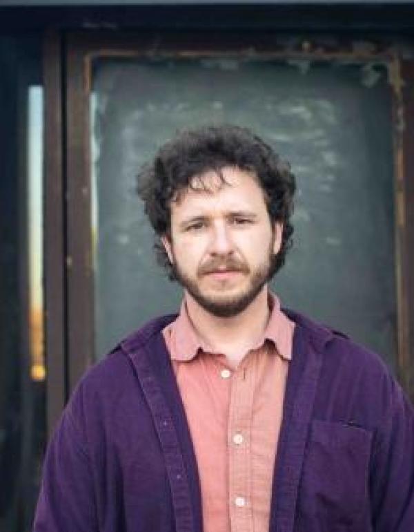 Lucas Murphy standing in front of doorway in pink and purple shirt