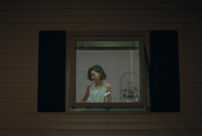 View through the window of woman washing dishes