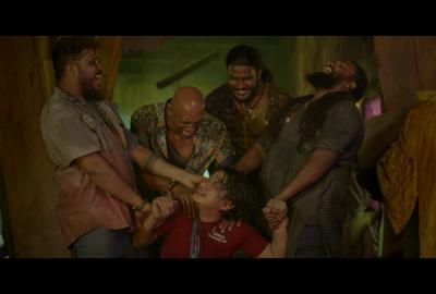 A group of men hold onto another man while laughing