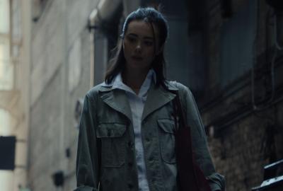 A woman looks down, wedged between dark and light. 