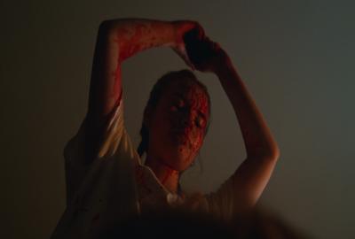 bloodied woman hold object above her head