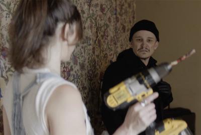 man looking at a power drill being held up by a woman