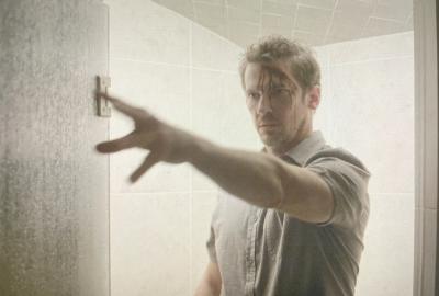 A man with blood dripping from his head presses a button