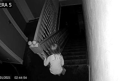 A camera shows a little girl looking down the staircase