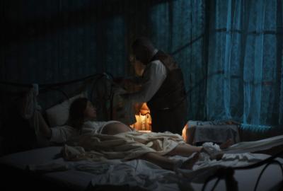 A man assist a pregnant woman in bed