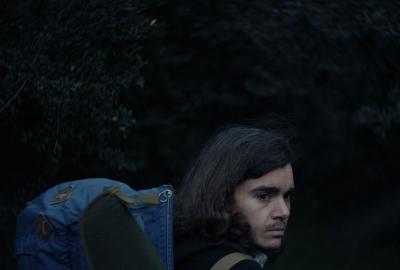 Elliot Fletcher with a backpack looks back