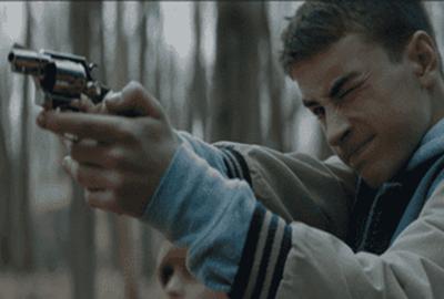 A young man points a gun