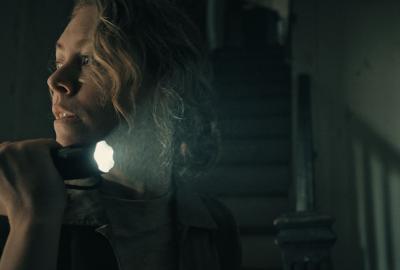 A woman looks back with a flashlight