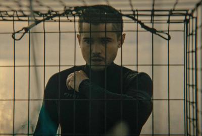 Lobsterman in a wetsuit stares at a lobster cage