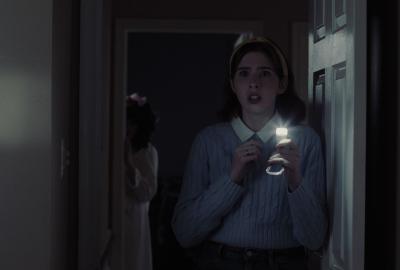 Muffy holds a flashlight inside a door.