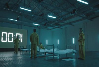 Four people in yellow outfits stand around beds