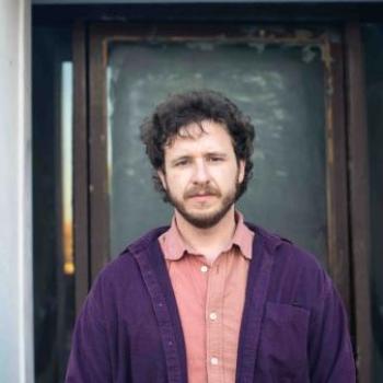 Lucas Murphy standing in front of doorway in pink and purple shirt